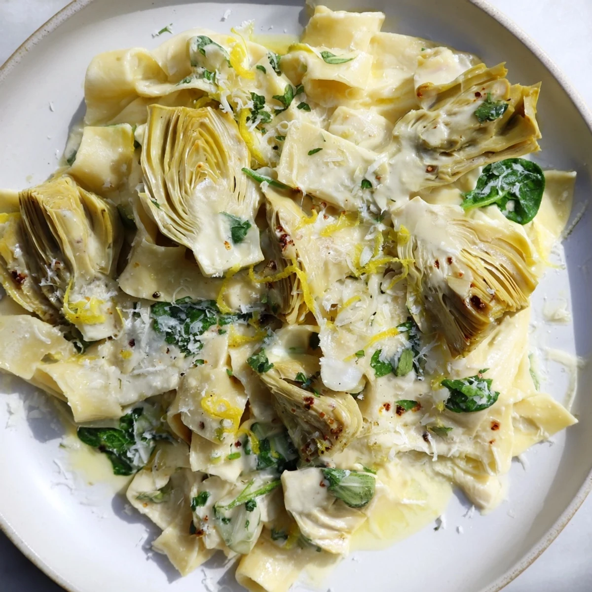 Golden, creamy Lemon Artichoke Pasta tossed with fresh basil, ready for a satisfying Italian meal.