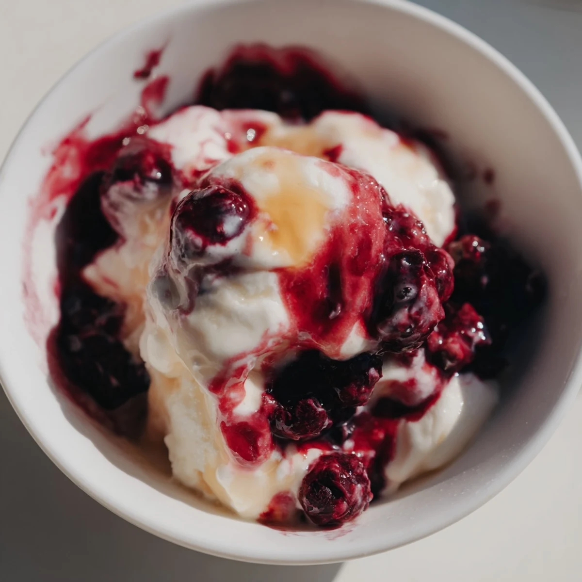A close-up of creamy cottage cheese ice cream swirled with vibrant frozen berries.