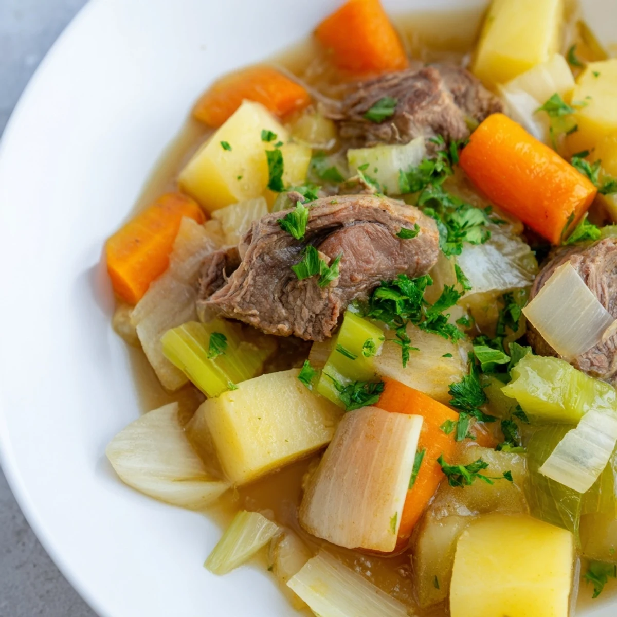 Tender chunks of lamb and hearty vegetables simmer in Welsh Cawl stew, a comforting meal.