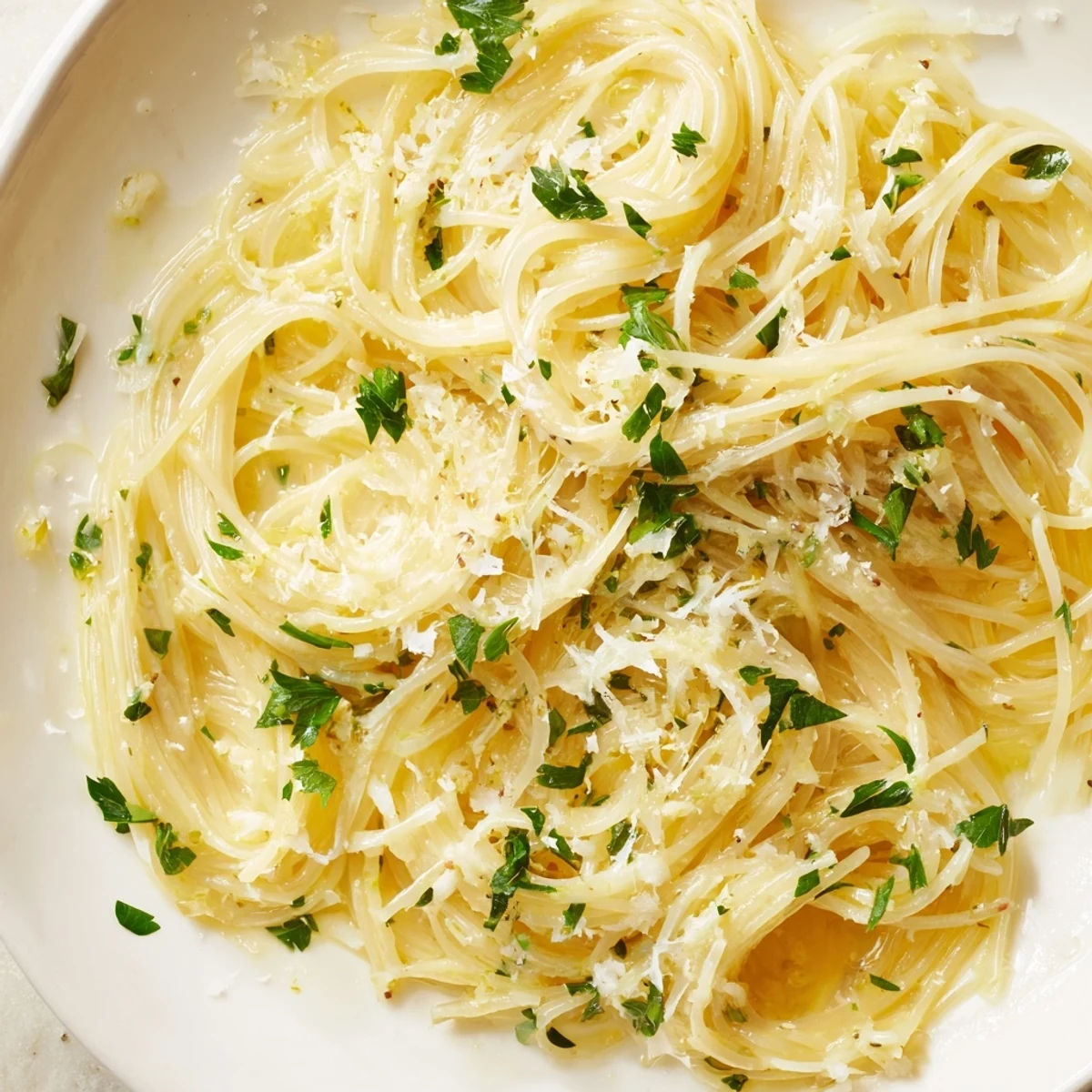 Delicious Lemon Butter Pasta Light served in a white bowl, topped with extra Parmesan and lemon zest.