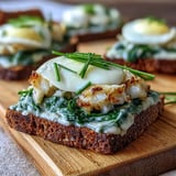 Perfectly poached smoked haddock layered with creamy spinach on toasted rye toasts, served warm with lemon wedges for brightness.