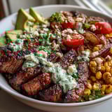 Sliced avocado, cherry tomatoes, and red onion add bright color to the Steak, Avocado, and Roasted Corn Bowl with Cilantro Cream Sauce.