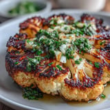 Charred cauliflower steaks served with vibrant chimichurri, offering a smoky and herbaceous vegan main dish.