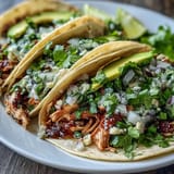 Juicy shredded chicken tacos ready with zesty salsa verde, perfect for taco night.