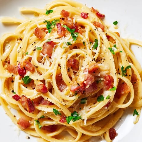 A close-up of Crispy Bacon Linguine with golden bacon bits and a glossy, creamy-looking sauce clinging to each al dente linguine noodle.