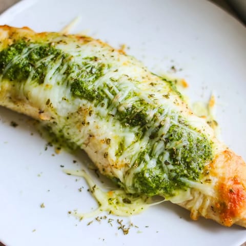 Juicy baked Mozzarella & Pesto Stuffed Chicken breasts with golden cheese bubbling out of a crisp crust.