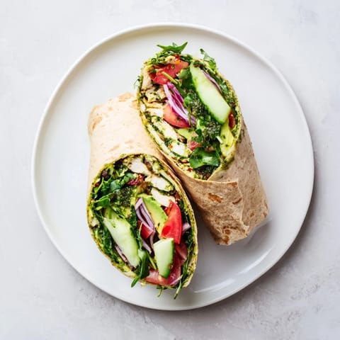 Freshly assembled Chimichurri Chicken Salad Wraps on a wooden board, garnished with extra herbaceous sauce and thinly sliced cucumber for a colorful, fresh presentation.