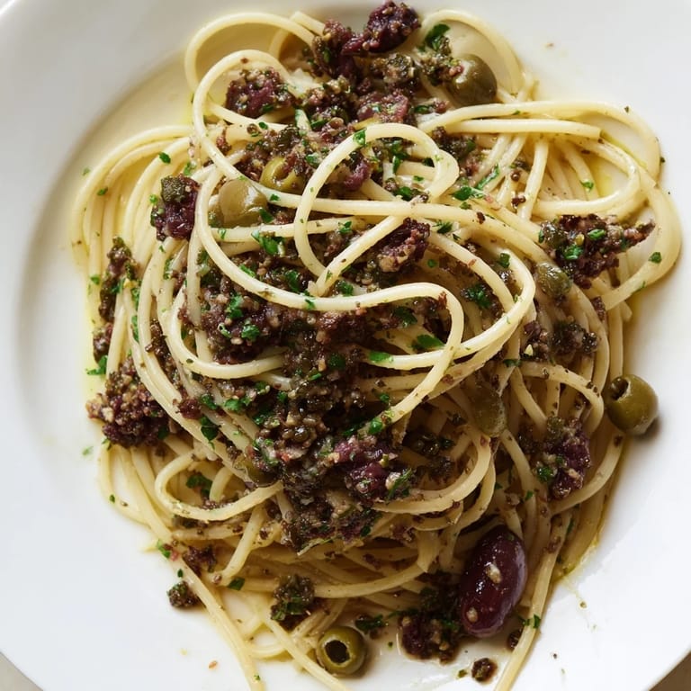 Savory olive tapenade pasta served on a white plate, showcasing a glossy sauce of olives, capers, and garlic, perfect for a quick and easy vegetarian dinner.