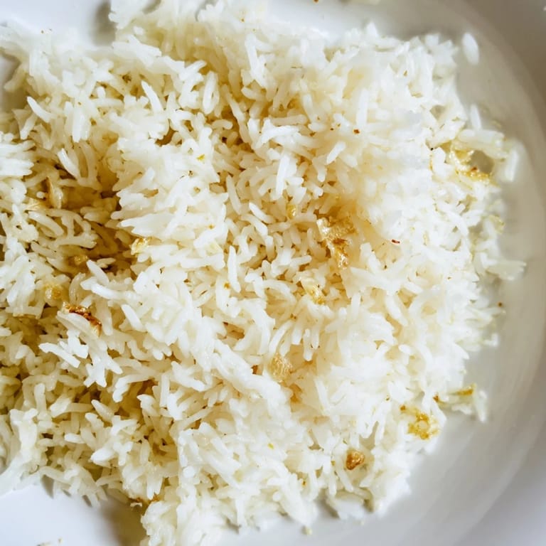 Savory garlic butter rice with grilled chicken breast, garnished with parsley and lemon wedges for a bright finish.