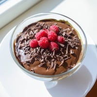 Creamy Avocado Chocolate Pudding, topped with fresh berries, a decadent vegan dessert.